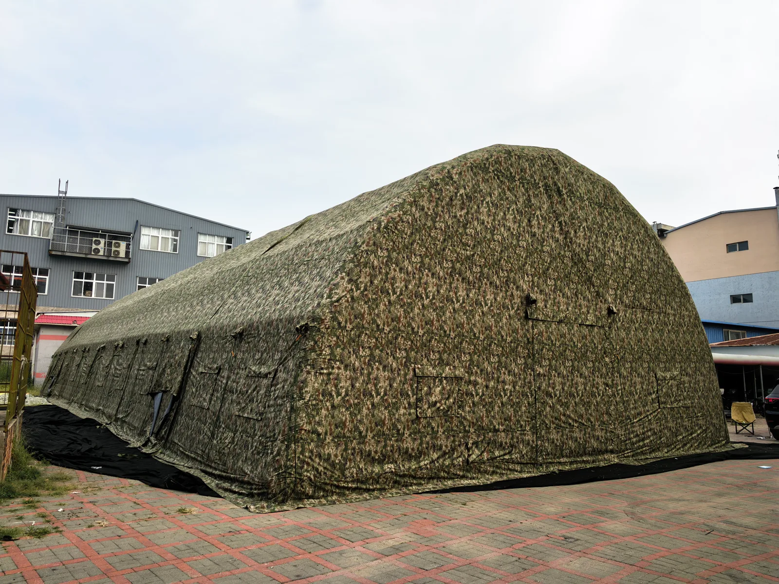 Camouflage-covered arched shelter photographed in the factory yard