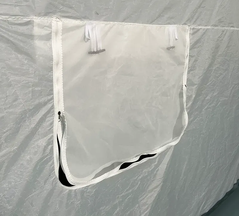 Close view of a white shelter wall with a zipped mesh window panel and fabric pull tabs
