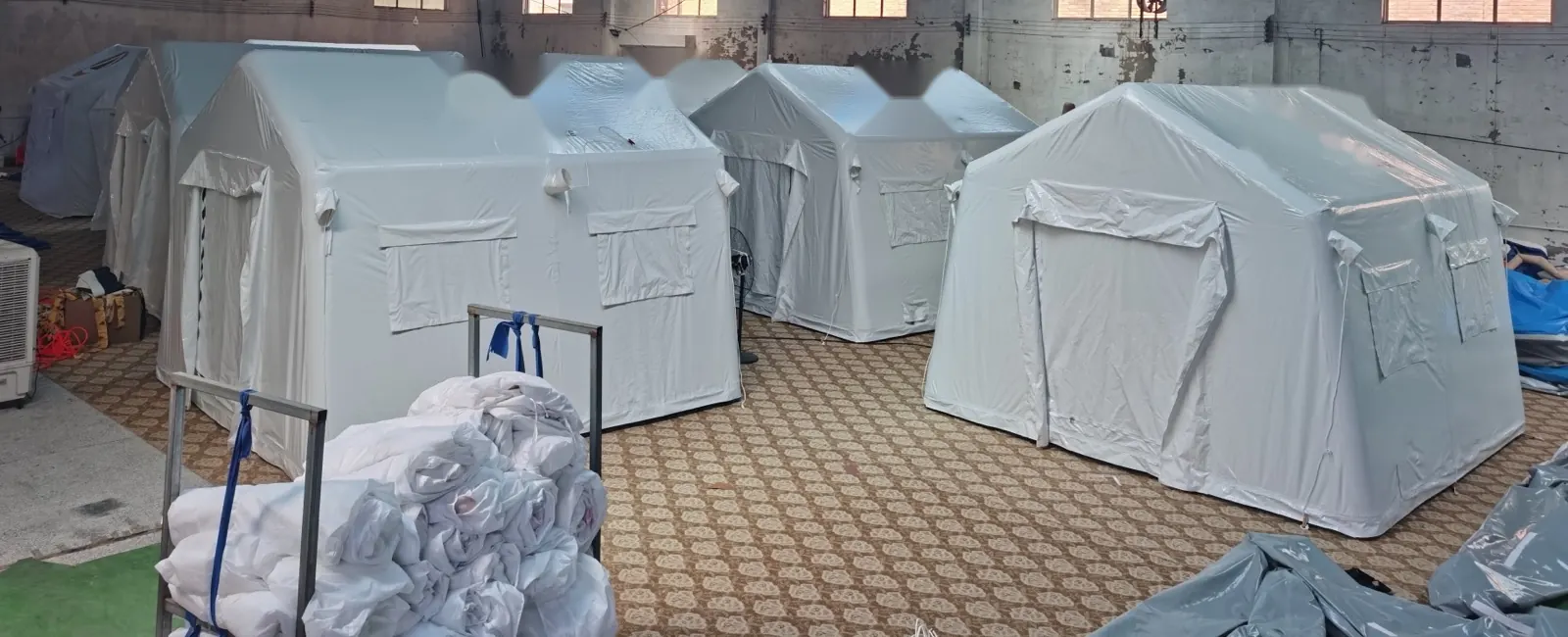 Finished white inflatable shelters lined up in a warehouse ahead of packing and shipment