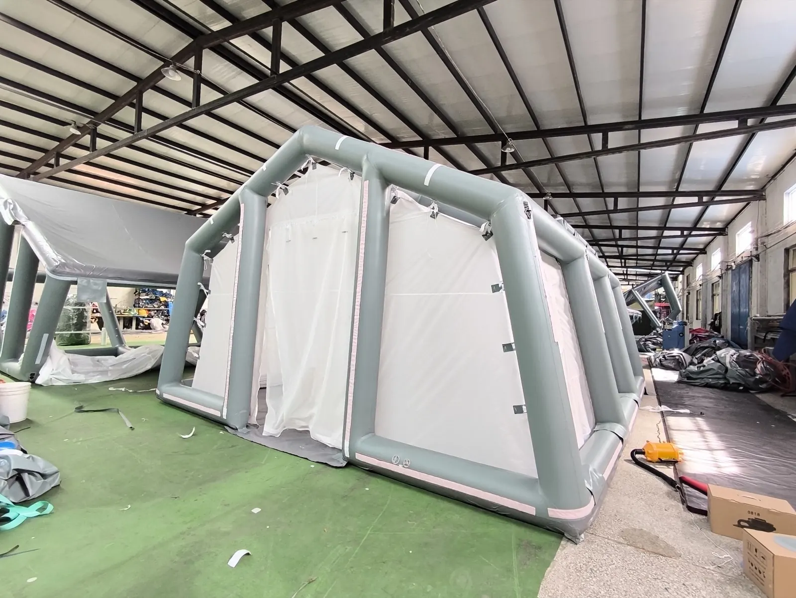 Grey air-beam shelter frame with white fabric walls and entrance assembled on a workshop floor