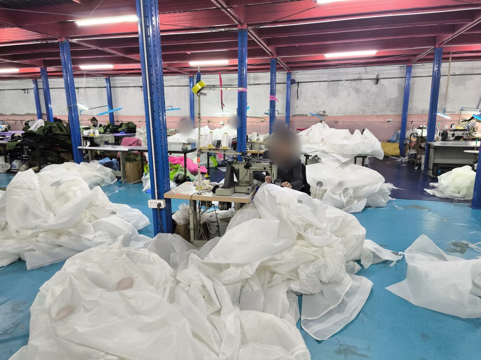 Industrial sewing machine in a workshop surrounded by large white tent panels