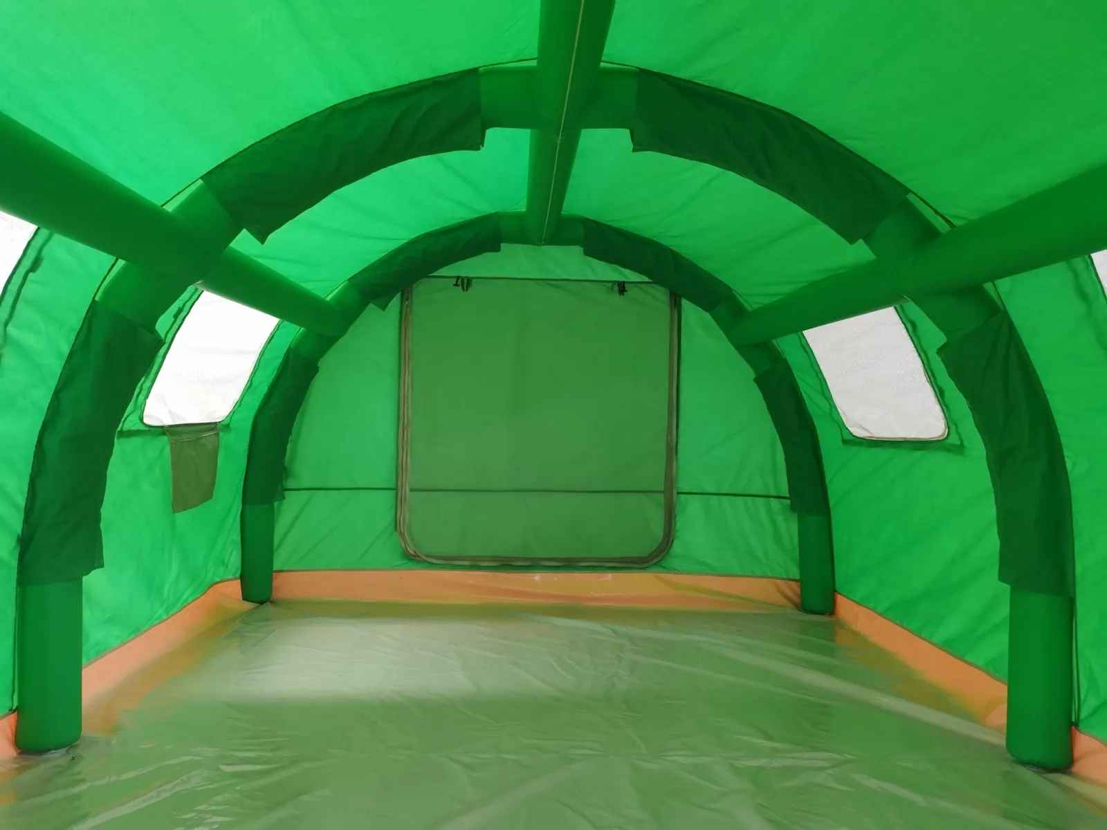 Interior view along green air-beam arches toward a rear panel with a mesh door