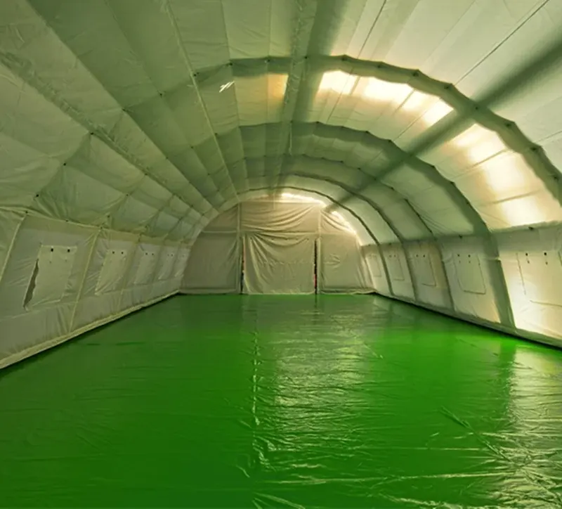 Interior of a long-span inflatable hall with green walls, an arched ceiling and a clear floor