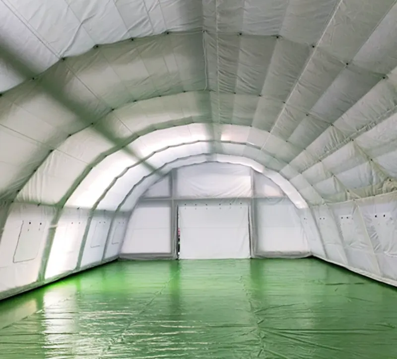 Interior of a white inflatable shelter with a ribbed arched ceiling and a green floor layer