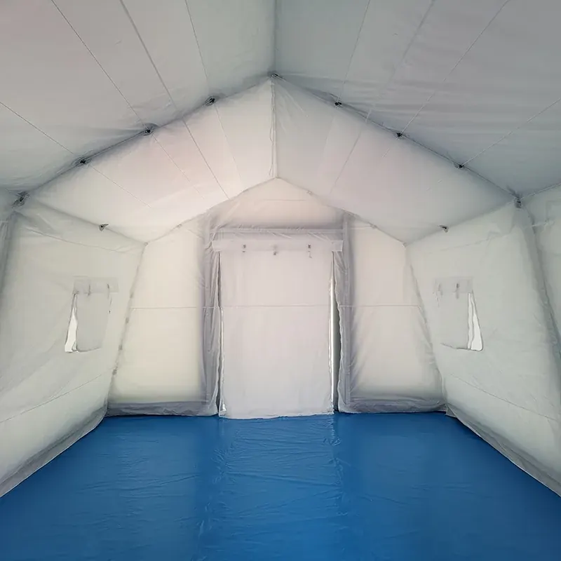 Interior of a small white inflatable shelter with a blue floor, a rear door panel and side windows