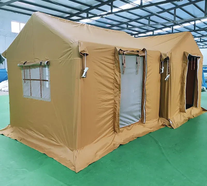 Sand-coloured inflatable shelter with a gable front and a window, standing in a workshop