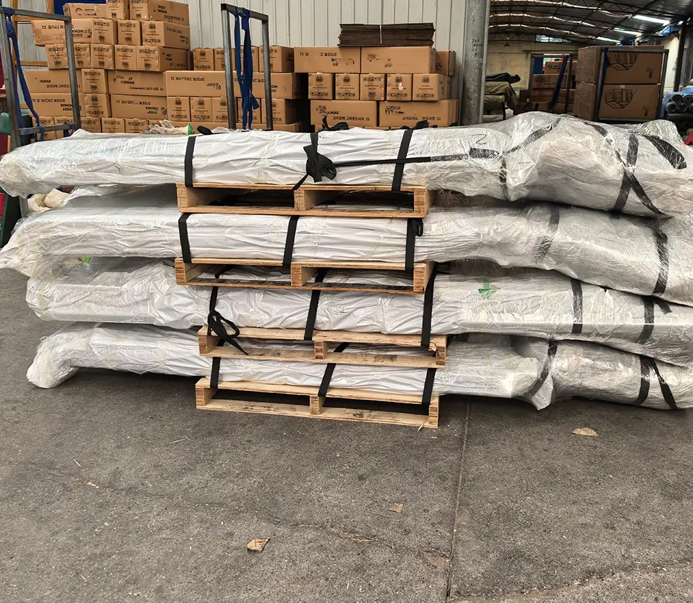 Stacks of shrink-wrapped shelter packs strapped on wooden pallets with cartons behind them
