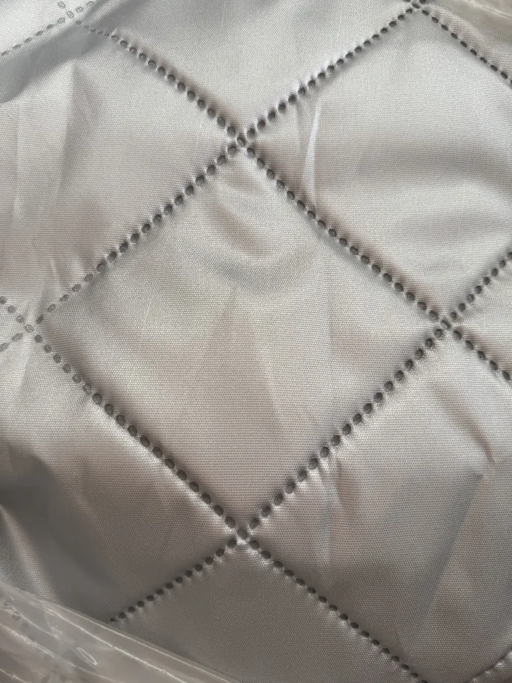 Close-up of grey quilted lining fabric with a diamond stitch pattern