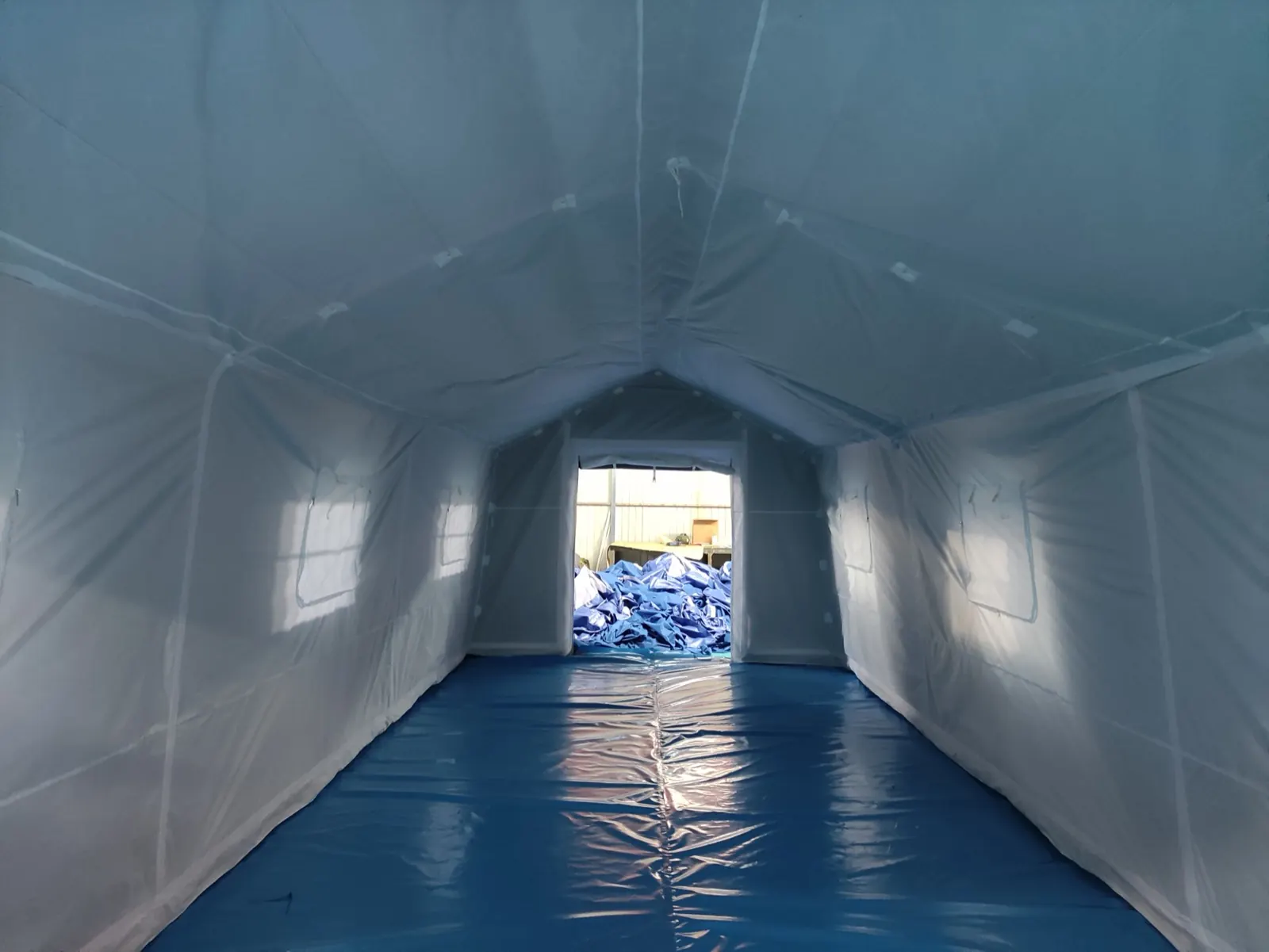 Interior of a relief shelter with white liner walls, ceiling attachment points and a blue floor layer
